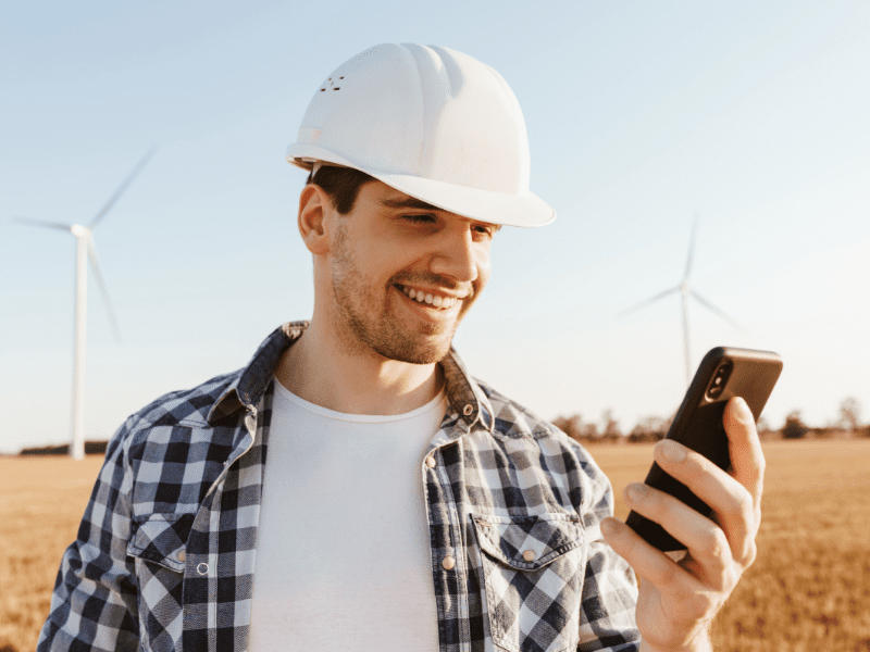 Man in a construction hat looking at a phone.