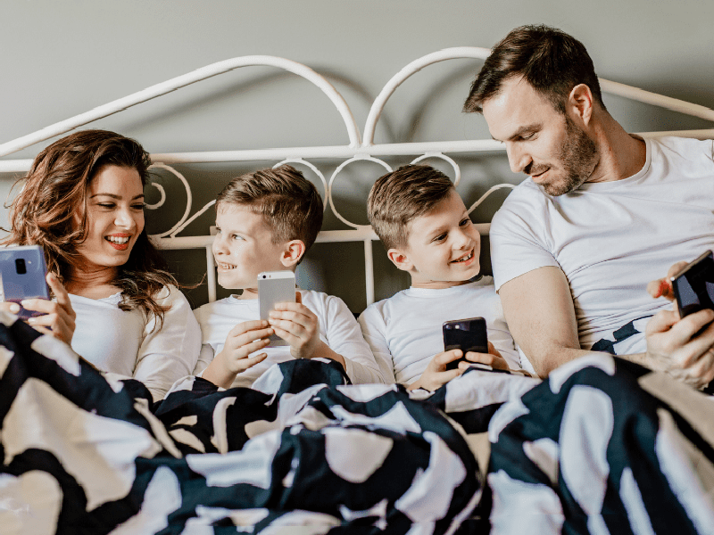 Family cuddling while playing on phones