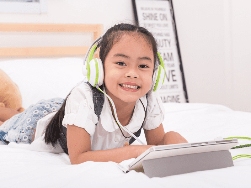 Girl smiling while using tablet.