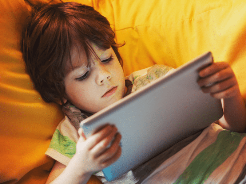 Kid on ipad in bed.