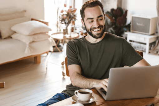 Man smiling while using his laptop.