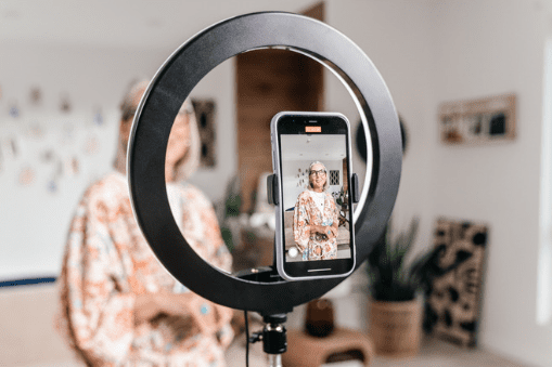 Woman filming with ring light on cellphone.