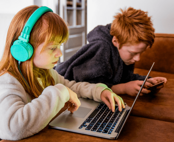 Two kids on computer and cellphone