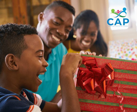 Boy opening a present while parents happily watch