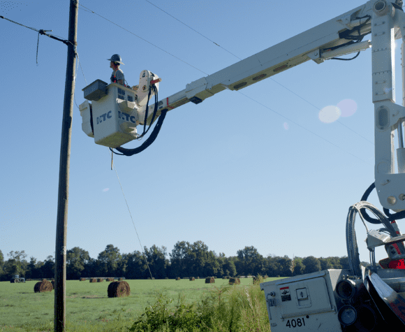 Serviceman in crane works on telephone pole