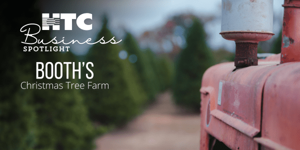 Close-up of tractor in front of rows of evergreen trees, with the text “HTC Business Spotlight: Booth’s Christmas Tree Farm"