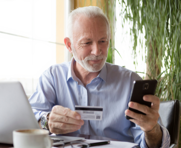 man with open laptop looking at phone, paying for service by credit card
