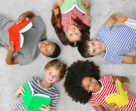 group of kids laying on the floor reading books