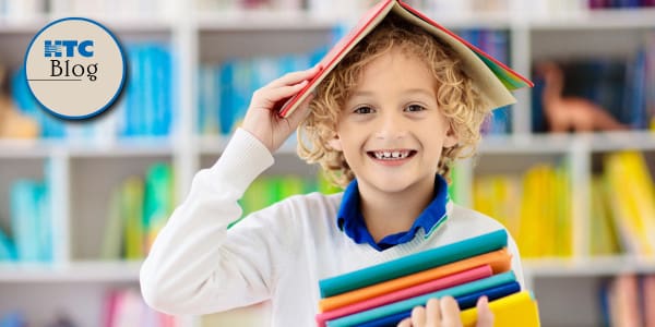 young boy in a library with a stack of books