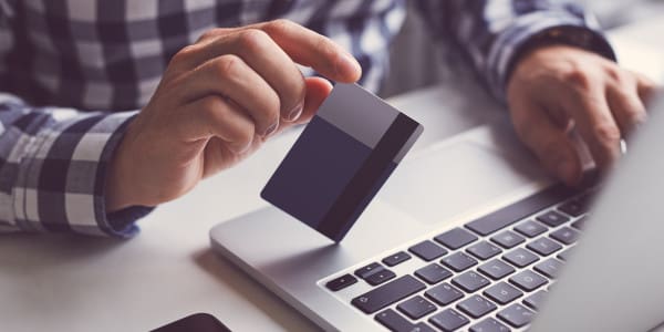 hands balancing credit card on laptop