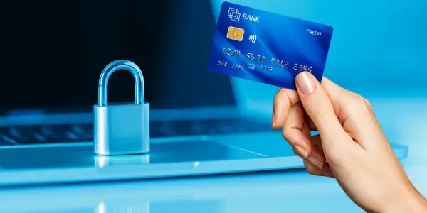 lock sitting on laptop and hand holding credit card