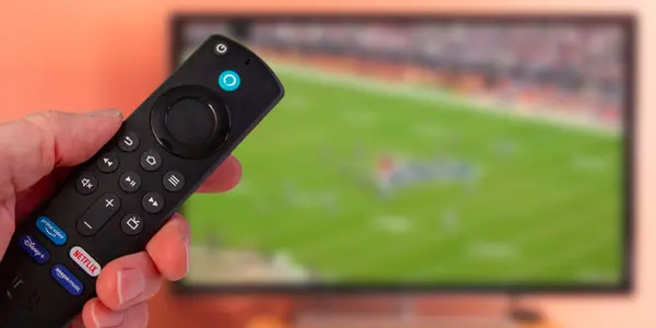 man holding amazon firestick 4k and watching sports