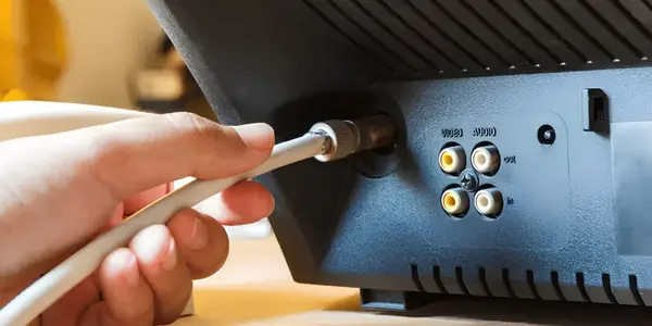 man plugging coax cable into TV