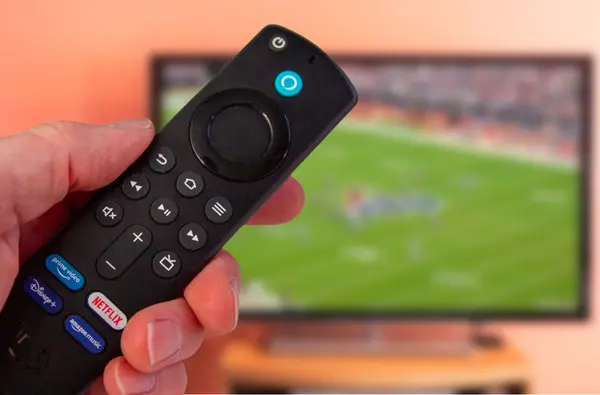 man holding amazon firestick 4k and watching sports